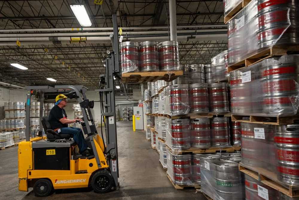 Photo of an operator driving a forktruck, stacking pallets of kegs Photo of an operator driving a forktruck, stacking pallets of kegs